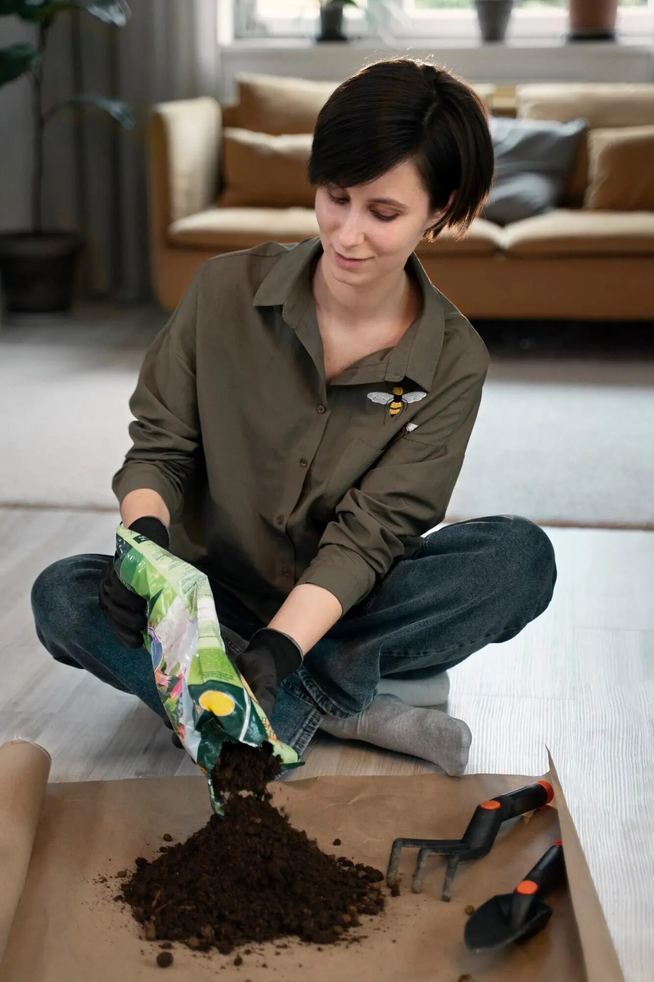 Ganzkörperaufnahme einer Frau mit einem Sack Blumenerde